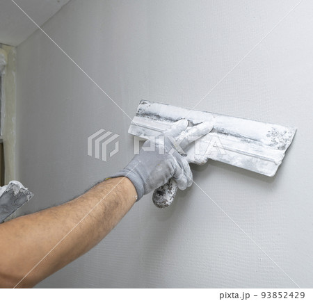 Plasterer applies plaster on the wall during repair and restoration work Plasterer applies plaster on the wall during repair and restoration work 93852429