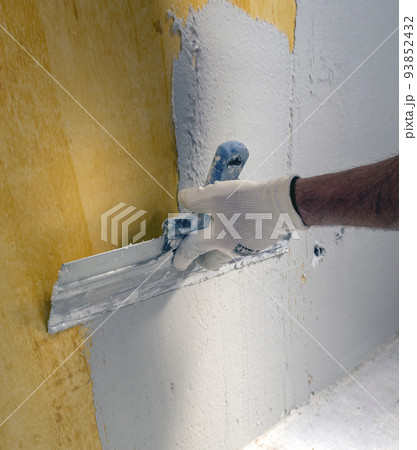 Plasterer applies plaster on the wall during repair and restoration work Plasterer applies plaster on the wall during repair and restoration work 93852432