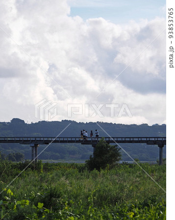 夏の入道雲を背景に川にかかる橋を歩く人々 夏の入道雲を背景に川にかかる橋を歩く人々 93853765