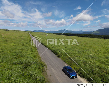 絶景の青空と草原に斜めに伸びる1本の道と青い自動車 絶景の青空と草原に斜めに伸びる1本の道と青い自動車 93853813