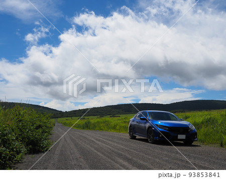 草原の砂利道を走る青い車 93853841
