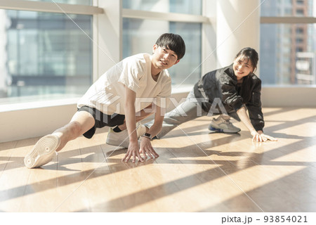 トレーナーに指導されながらストレッチする男性 トレーナーに指導されながらストレッチする男性 93854021
