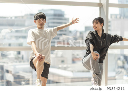 トレーナーに指導されながらストレッチする男性 93854211