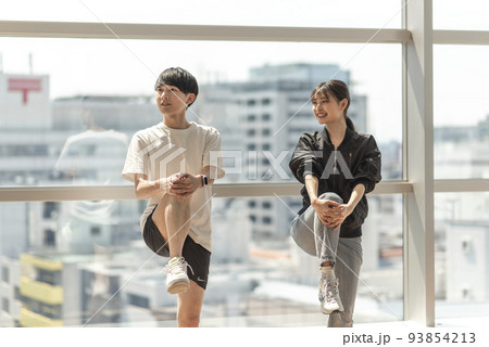 トレーナーに指導されながらストレッチする男性 トレーナーに指導されながらストレッチする男性 93854213