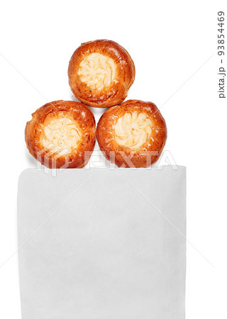 Cheesecakes protrude from a white paper bag. Three juicy cheesecakes with cottage cheese on a white background. Buns with cottage cheese. Space for a logo. 93854469
