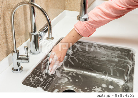 Foam and hand with cleaning sponge on kitchen sink 93854555