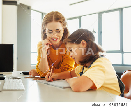 Cheerful mother doing homework with daughter at home 93855681