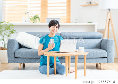 リビングでノートPCを使う女性。 93857418