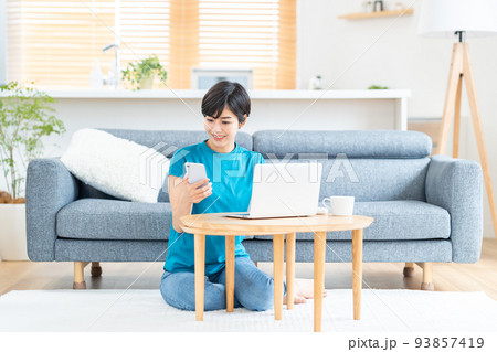 リビングでノートPCを使う女性。 93857419