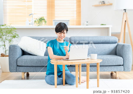 リビングでノートPCを使う女性。 93857420
