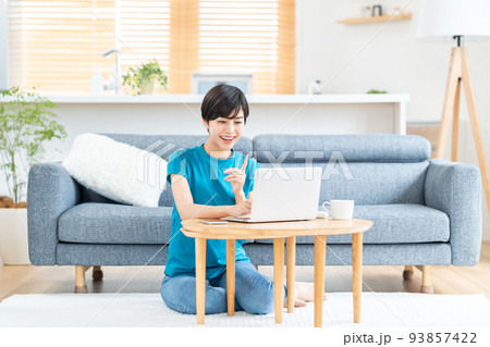 リビングでノートPCを使う女性。 93857422