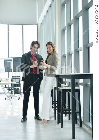 happy  busimess Asian man and woman looking at mobile phone for relaxing after work in office 93857542