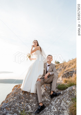 Pretty bride and stylish groom. Beautifull wedding couple embracing near the shore of a mountain river with stones. Wedding at Bakota in Ukraine. 93857850