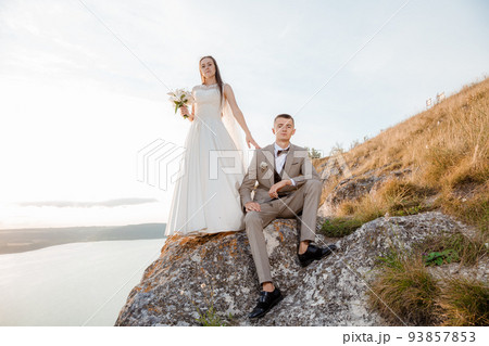 Pretty bride and stylish groom. Beautifull wedding couple embracing near the shore of a mountain river with stones. Wedding at Bakota in Ukraine. 93857853