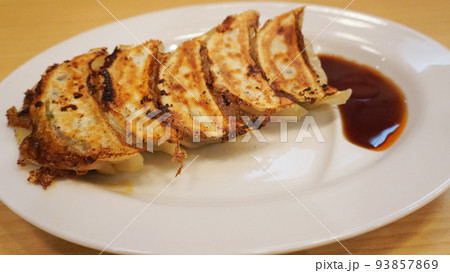 お皿に盛られた餃子とタレ 93857869