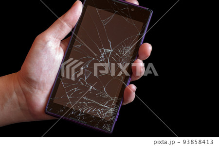 Smartphone with highly broken screen in women hand on black background. 93858413