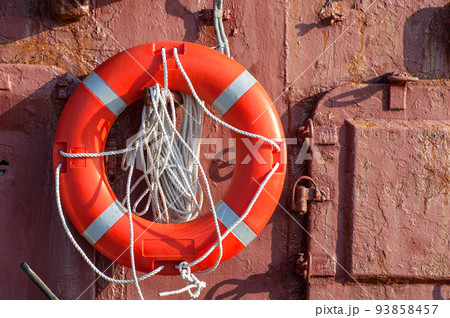The lifebuoy with cord is hanged on metal wall on the ship. The lifebuoy with cord is hanged on metal wall on the ship. 93858457