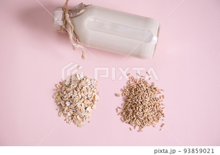 Flat lay Heap of oat groats, oat-flakes and bottle of plant based organic healthy vegan wholesome milk on pink surface. Flat lay Heap of oat groats, oat-flakes and bottle of plant based organic healthy vegan wholesome milk on pink surface. 93859021