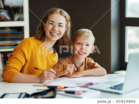 Cheerful mother doing homework with son at home Cheerful mother doing homework with son at home 93859969