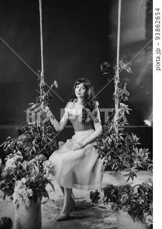 a woman in a dress on a swing in peony flowers. solar glare. black and white a woman in a dress on a swing in peony flowers. solar glare. black and white 93862654