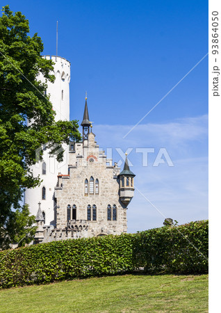 Photo of lichtenstein castle or Schloss on forested rock cliff in Swabian Alps in summer. Seasonal panorama of romantic fairytale palace in Gothic revival style over sky. European famous landmark 93864050