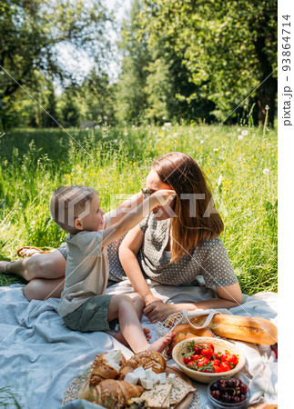 Family mom and son on picnic. Smiling and enjoying summer on blanket in park. Family mom and son on picnic. Smiling and enjoying summer on blanket in park. 93864714