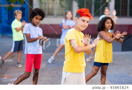 Children exercising contemporary dance moves outdoors 93865824