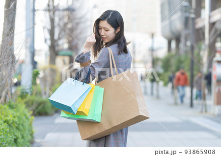 たくさんの買い物袋を抱える女性 93865908