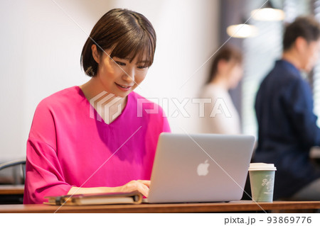 コーヒーを飲みながら、コワーキングスペースで働く若い女性 コーヒーを飲みながら、コワーキングスペースで働く若い女性 93869776