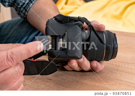 Photographer placing an sd memory card in a professional still camera. 93870851