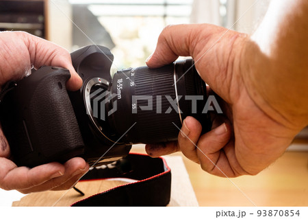 Photographer attaching a lens to a professional still camera. Photographer attaching a lens to a professional still camera. 93870854