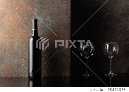 Bottle of red wine with empty wine glasses on rusty brown background. 93871373