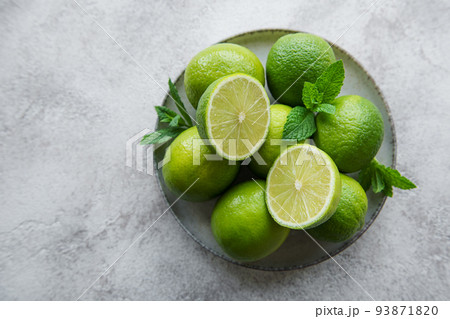 Green Limes with fresh mint leaves on plate Green Limes with fresh mint leaves on plate 93871820