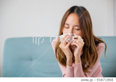 Ill Asian young woman cold covered with blanket sitting on sofa 93871968