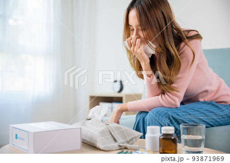 Asian young girl cold sick she sneeze with tissue paper on sofa Asian young girl cold sick she sneeze with tissue paper on sofa 93871969