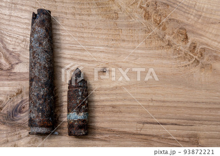 old rusty artillery shell and aircraft projectile on wooden background, shells bullets of world war 2 found, digged out from the ground old rusty artillery shell and aircraft projectile on wooden background, shells bullets of world war 2 found, digged out from the ground 93872221