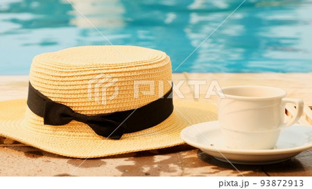 cup of coffee and a straw hat on the background of a swimming pool on a summer sunny day. Good 93872913