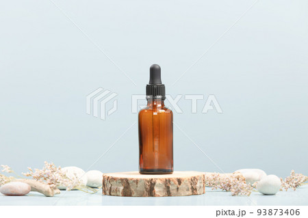 Amber glass transparent bottle on wooden podium with natural stones and plants 93873406