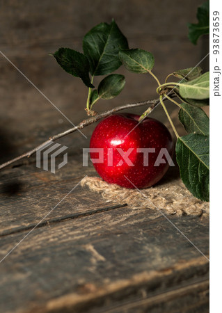 Red apple with leaves on burlap on wooden boards Red apple with leaves on burlap on wooden boards 93873659
