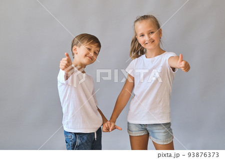 Cute two kids, little boy and girl in white t-shirts on gray background 93876373