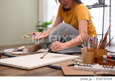 Casual young woman painting art picture with watercolor on canvas, enjoy creativity activity at home. Art, hobby and leisure activity concept Casual young woman painting art picture with watercolor on canvas, enjoy creativity activity at home. Art, hobby and leisure activity concept 93876494