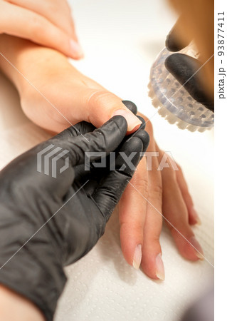 Hands of the manicure master removing dust from nails with a brush cleaning nails in a nail salon 93877411