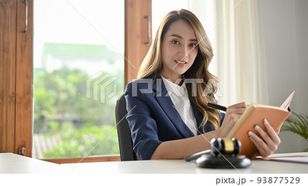 Attractive Asian female lawyer notes something on her personal book planner. Attractive Asian female lawyer notes something on her personal book planner. 93877529