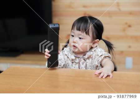 テレビのリモコンをいたずらする1歳の女の子 テレビのリモコンをいたずらする1歳の女の子 93877969