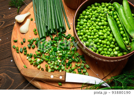 green onions, dill and peas on a wooden background, still life, sliced vegetables on a kitchen board, concept of fresh and healthy food green onions, dill and peas on a wooden background, still life, sliced vegetables on a kitchen board, concept of fresh and healthy food 93880190