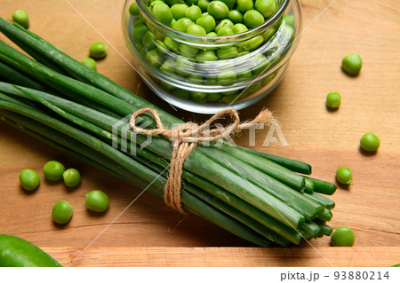 vegetables on a wooden kitchen board, sliced green onions, peas on a wood background, concept of fresh and healthy food, still life 93880214
