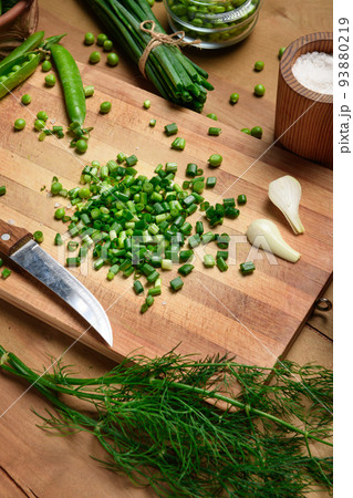vegetables on a wooden kitchen board, sliced green onions, dill and peas on a wood background, concept of fresh and healthy food, still life 93880219