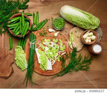 vegetables on a wooden kitchen board, green onions, dill and peas, sliced cabbage on a wood background, concept of fresh and healthy food, still life 93880227