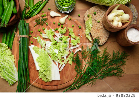 vegetables on a wooden kitchen board, green onions, dill and peas, sliced cabbage on a wood background, concept of fresh and healthy food, still life 93880229