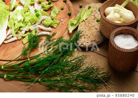 vegetables on a wooden kitchen board, green onions, dill and peas, sliced cabbage on a wood background, concept of fresh and healthy food, still life 93880240